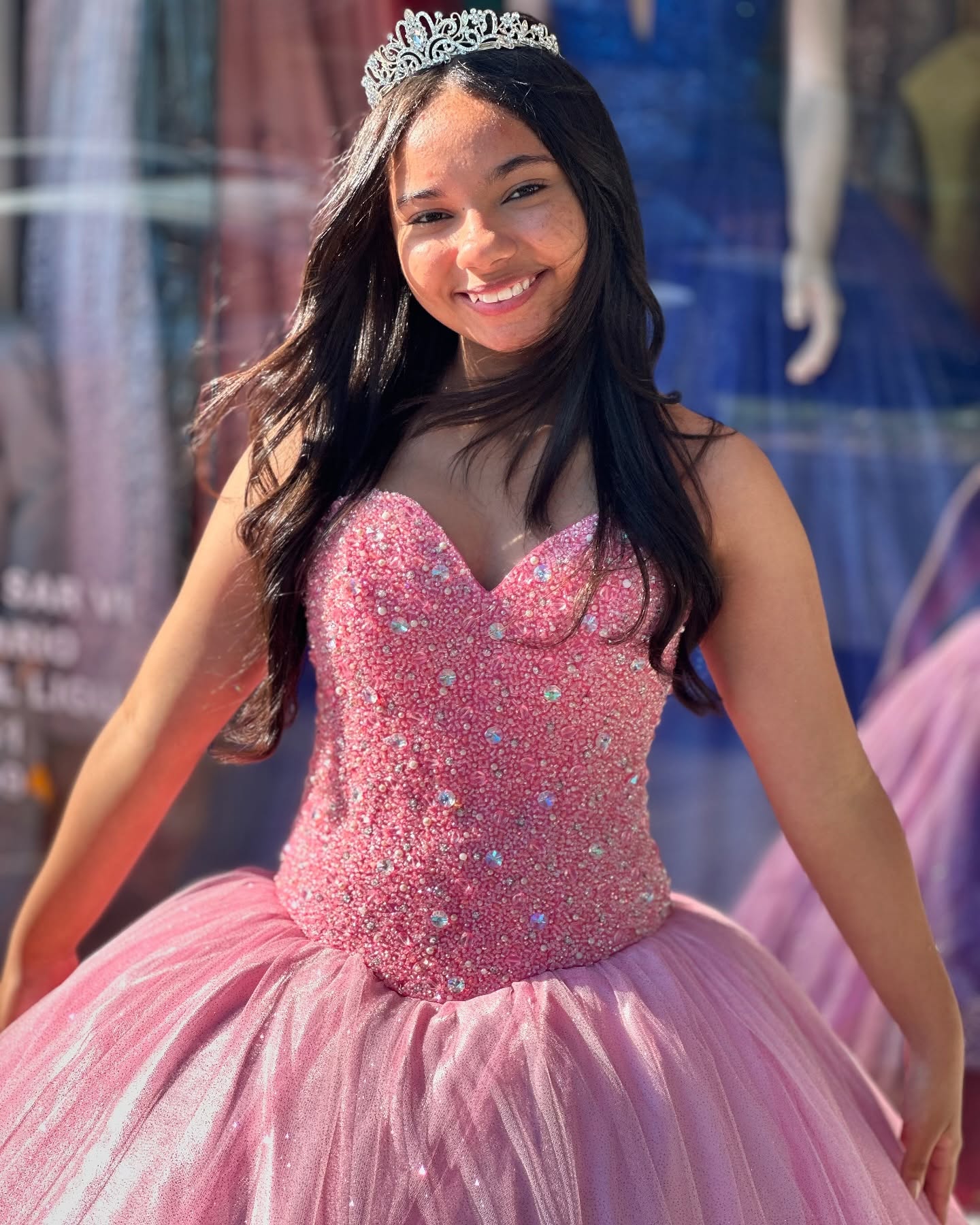 Debutante sorrindo com vestido rosa bordado e coroa